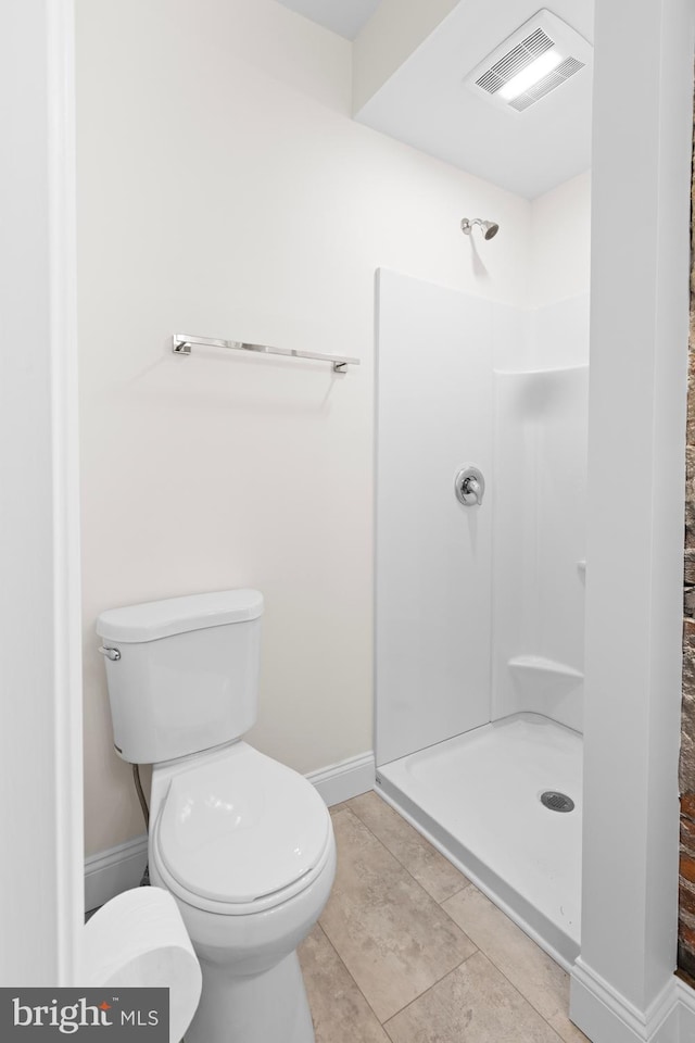 bathroom featuring tile patterned floors, toilet, and walk in shower