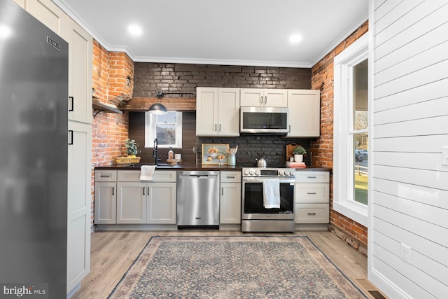 kitchen featuring crown molding, sink, stainless steel appliances, and light hardwood / wood-style flooring