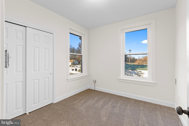 unfurnished bedroom with carpet flooring, a closet, and multiple windows