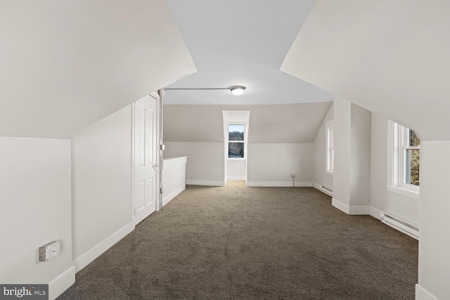 bonus room with dark colored carpet, a healthy amount of sunlight, vaulted ceiling, and a baseboard heating unit