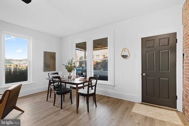 dining space with light hardwood / wood-style floors and brick wall