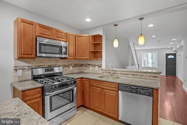 kitchen featuring appliances with stainless steel finishes, kitchen peninsula, light tile patterned floors, pendant lighting, and sink