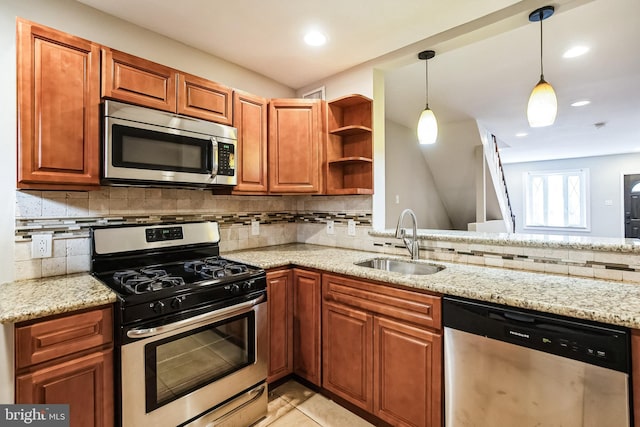 kitchen with light stone counters, stainless steel appliances, and sink