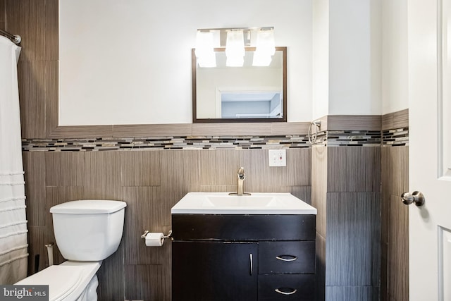 bathroom with tile walls, vanity, and toilet