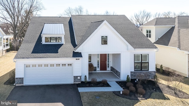 modern inspired farmhouse with aphalt driveway, stone siding, covered porch, and roof with shingles