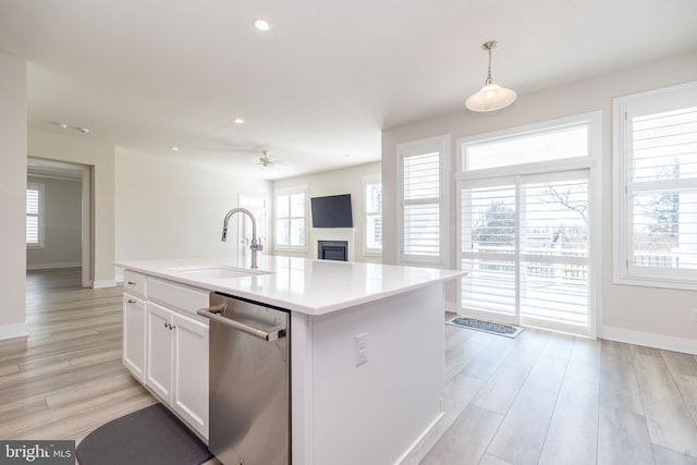 kitchen featuring stainless steel dishwasher, light wood-type flooring, white cabinetry, and a sink