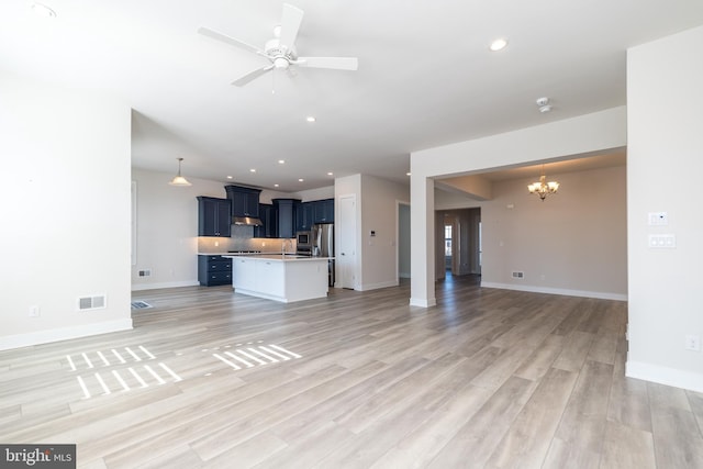 unfurnished living room featuring recessed lighting, visible vents, ceiling fan with notable chandelier, and light wood-style floors