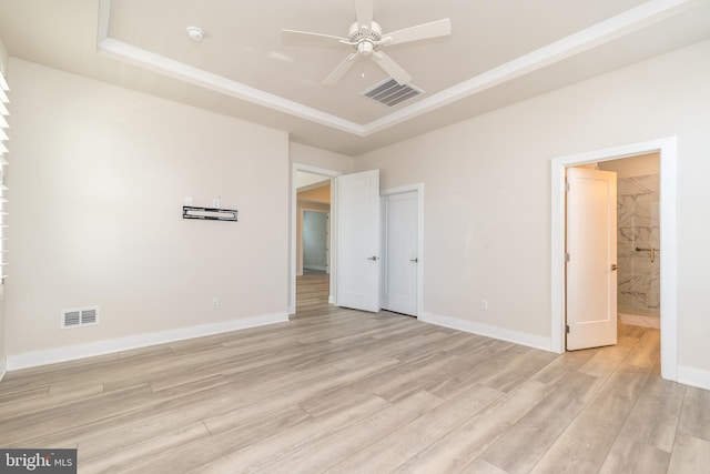 unfurnished bedroom featuring a raised ceiling, visible vents, and light wood finished floors