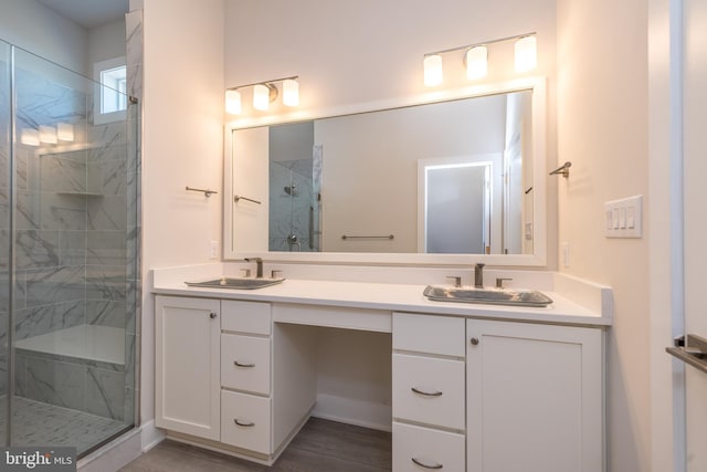 full bathroom featuring double vanity, a marble finish shower, and a sink