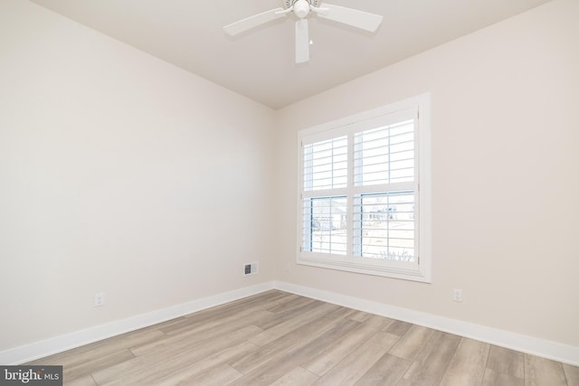 empty room featuring a ceiling fan, light wood-style floors, visible vents, and baseboards