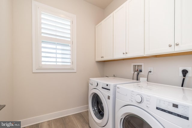 washroom featuring baseboards, cabinet space, light wood-style flooring, and washer and clothes dryer