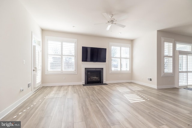 unfurnished living room with visible vents, a fireplace with flush hearth, light wood-style floors, and baseboards