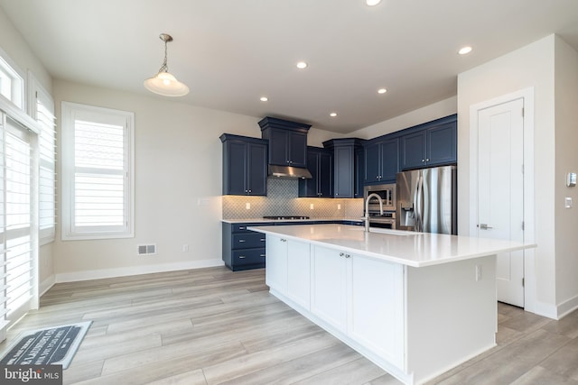 kitchen with visible vents, blue cabinetry, light countertops, appliances with stainless steel finishes, and tasteful backsplash