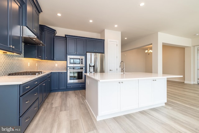 kitchen with blue cabinets, stainless steel appliances, tasteful backsplash, and light countertops