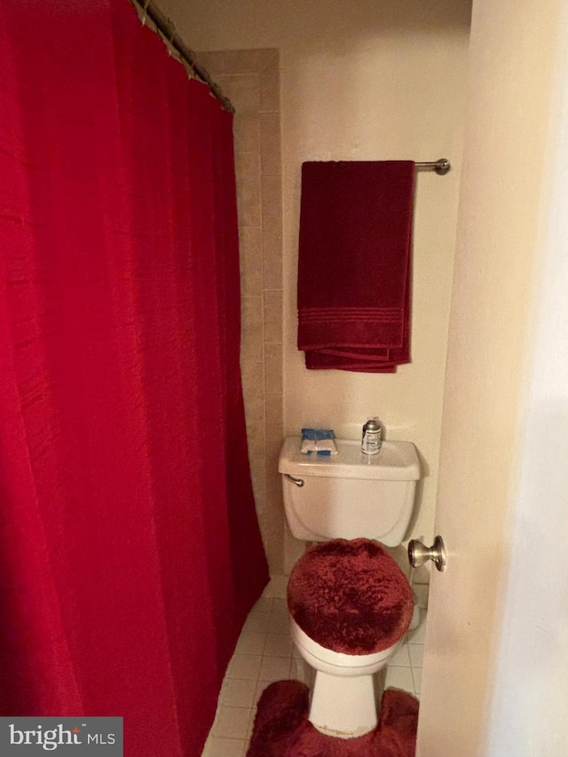 bathroom featuring tile patterned flooring, toilet, and curtained shower