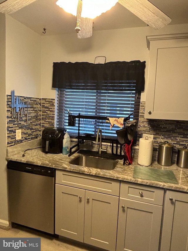 kitchen with dishwasher, tasteful backsplash, light stone counters, and sink