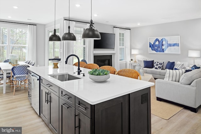 kitchen featuring pendant lighting, a center island with sink, light wood-type flooring, and sink