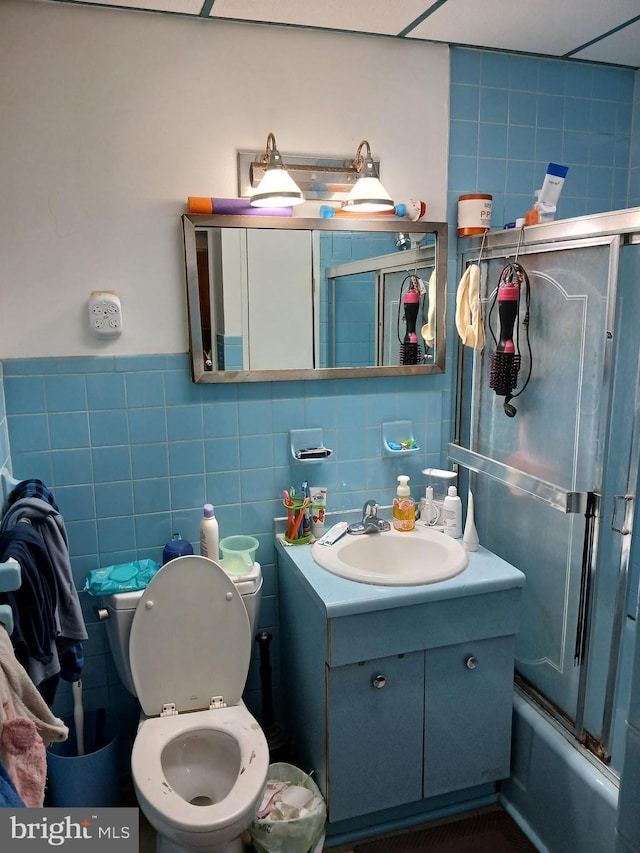 full bathroom with vanity, toilet, enclosed tub / shower combo, and tile walls