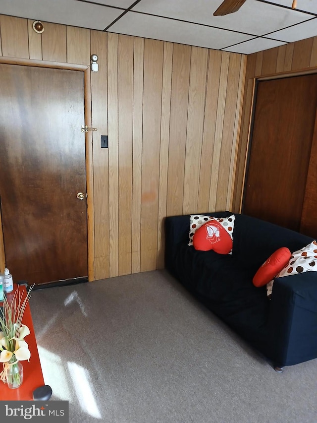 bedroom with a paneled ceiling, wood walls, and carpet