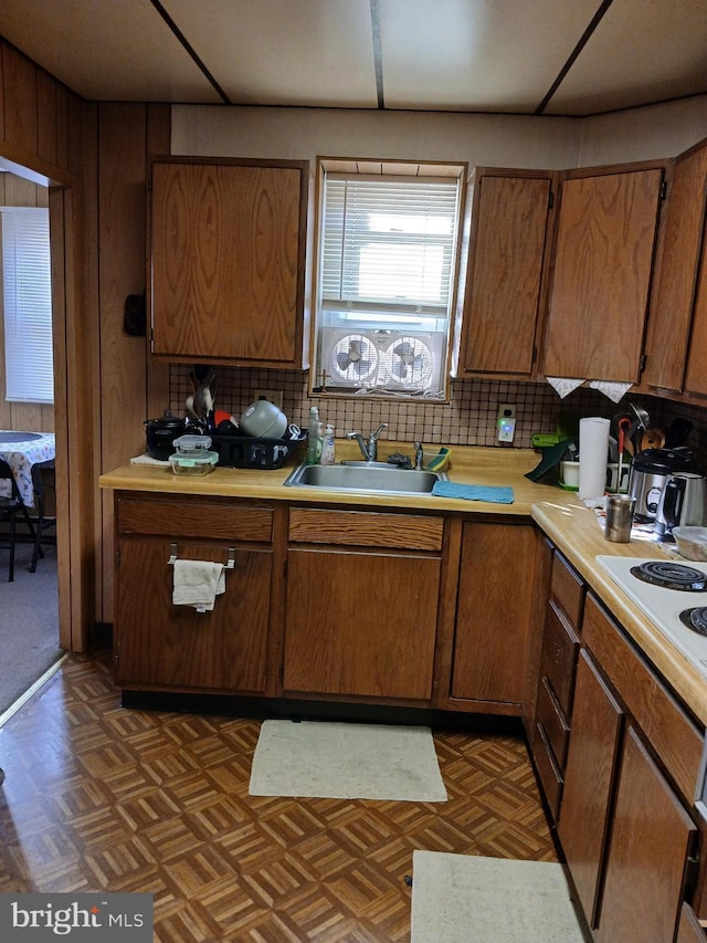 kitchen with decorative backsplash, white stovetop, dark parquet flooring, and sink