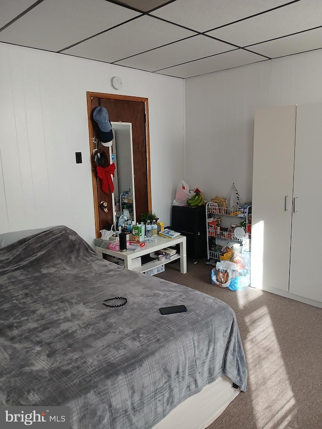 carpeted bedroom featuring a drop ceiling