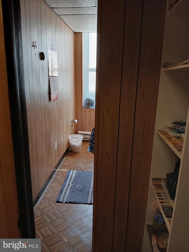 bathroom featuring parquet flooring, a textured ceiling, baseboard heating, and wooden walls