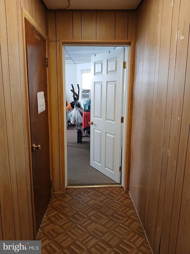 hallway with wood walls and dark parquet flooring