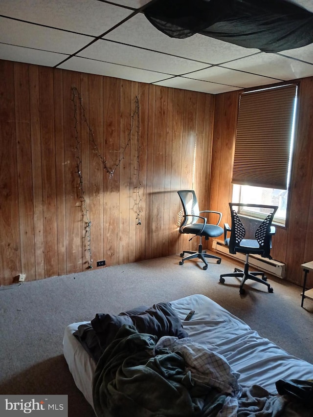 bedroom featuring carpet flooring, wood walls, and a drop ceiling