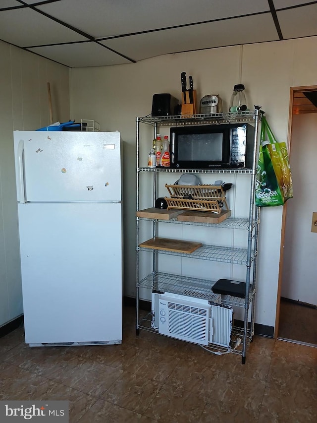 interior space with a paneled ceiling and white fridge