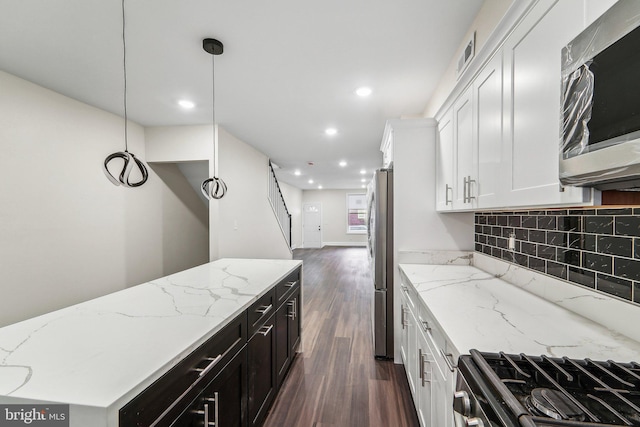 kitchen with dark wood-type flooring, white cabinets, appliances with stainless steel finishes, decorative light fixtures, and light stone counters