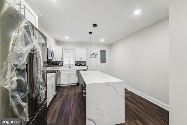 kitchen with appliances with stainless steel finishes, decorative light fixtures, a center island, dark hardwood / wood-style floors, and white cabinetry