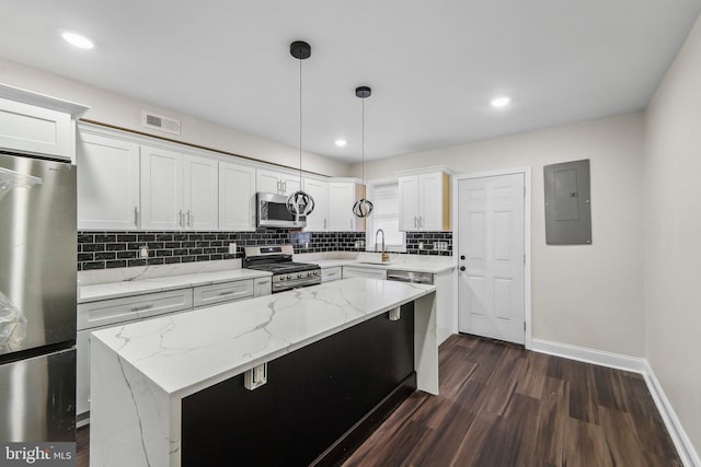 kitchen featuring appliances with stainless steel finishes, pendant lighting, white cabinetry, electric panel, and a kitchen island