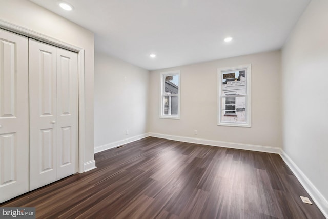 unfurnished bedroom with a closet and dark wood-type flooring