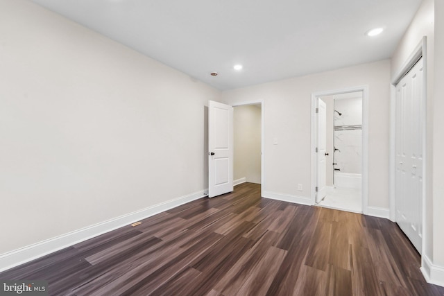 unfurnished bedroom with ensuite bathroom and dark wood-type flooring