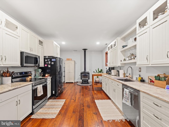 kitchen with white cabinets, a wood stove, dark wood-type flooring, and appliances with stainless steel finishes