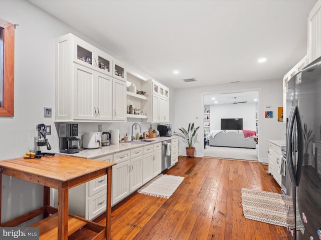 kitchen featuring sink, ceiling fan, white cabinetry, wood-type flooring, and stainless steel appliances