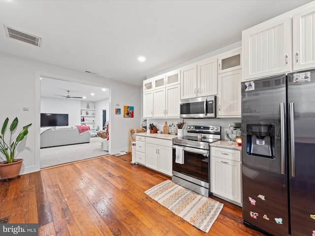 kitchen featuring white cabinets, hardwood / wood-style floors, stainless steel appliances, and ceiling fan