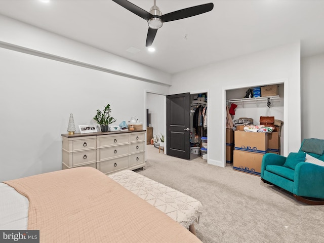 bedroom with light colored carpet, ceiling fan, and multiple closets