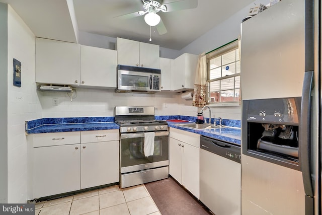 kitchen with white cabinets, sink, decorative backsplash, light tile patterned flooring, and stainless steel appliances