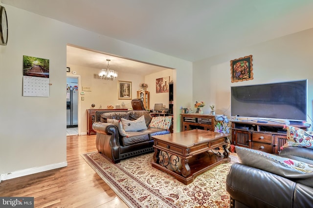 living room featuring light wood-type flooring and a notable chandelier