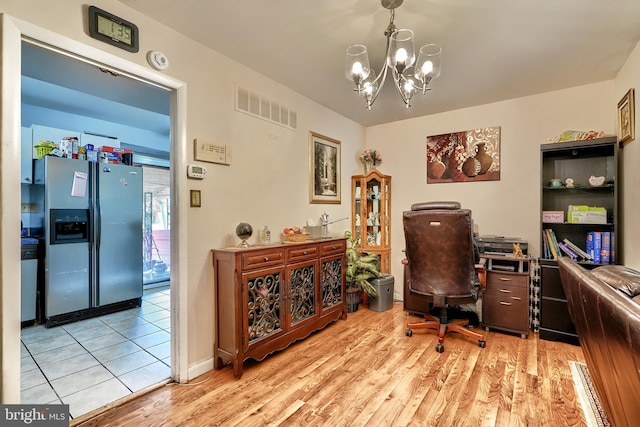 home office with light wood-type flooring and an inviting chandelier