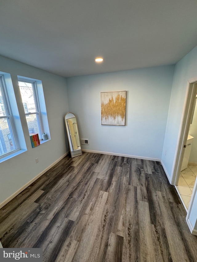 unfurnished bedroom featuring dark hardwood / wood-style floors and ensuite bath