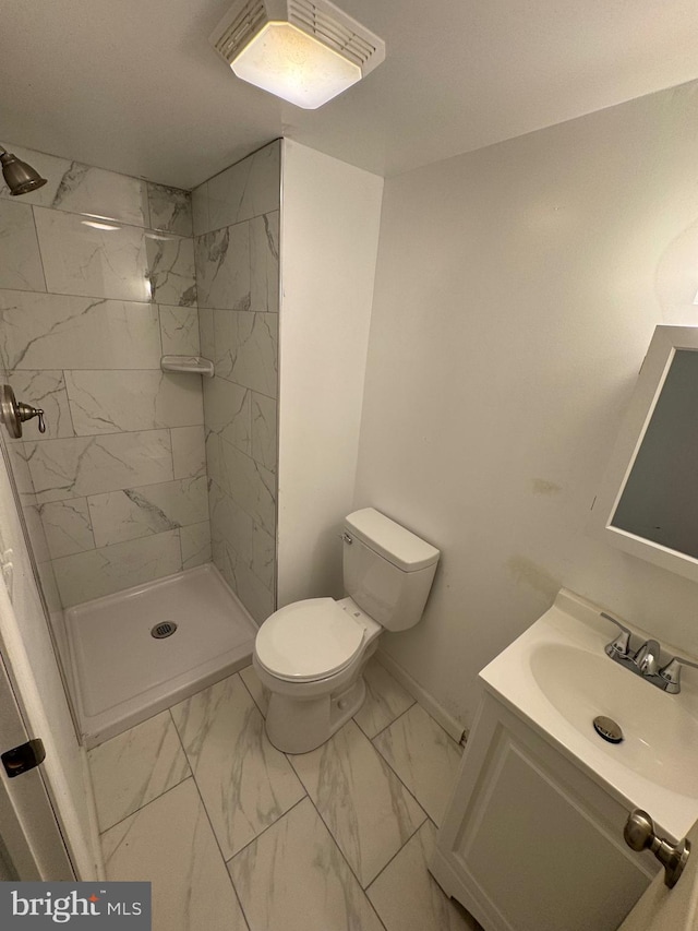 bathroom with toilet, vanity, and tiled shower