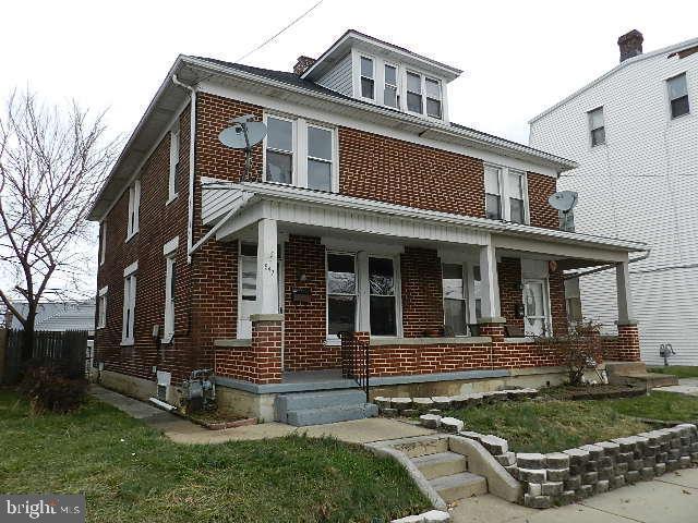 american foursquare style home with a porch and brick siding