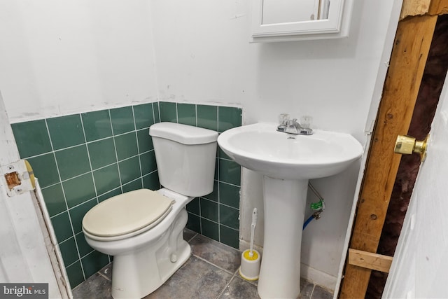 half bathroom featuring toilet, a wainscoted wall, and tile walls