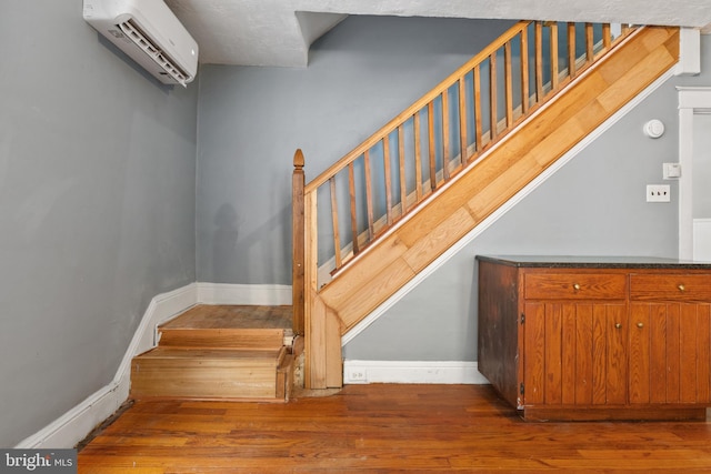 staircase with baseboards, wood finished floors, and a wall mounted air conditioner