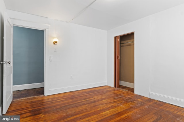 unfurnished bedroom featuring a closet, baseboards, and dark wood-style flooring