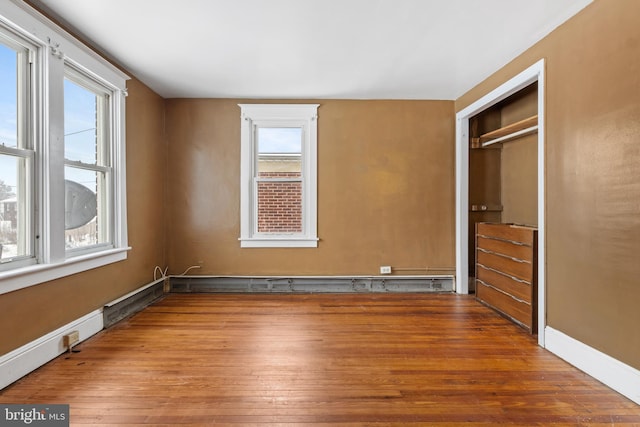 unfurnished bedroom featuring a closet, wood finished floors, and baseboards