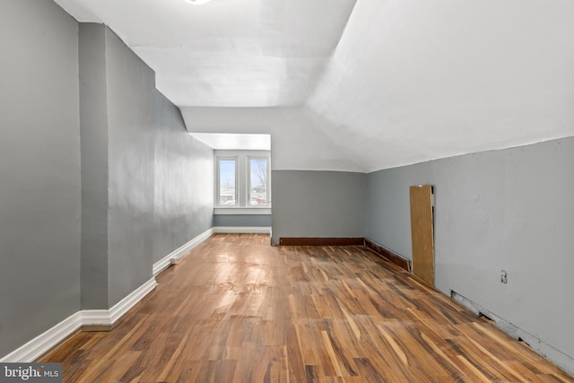 bonus room with vaulted ceiling, wood finished floors, and baseboards