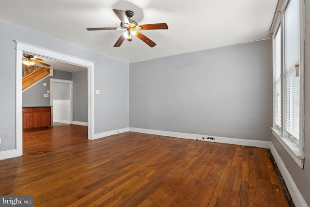 spare room featuring dark wood-style floors, ceiling fan, and baseboards